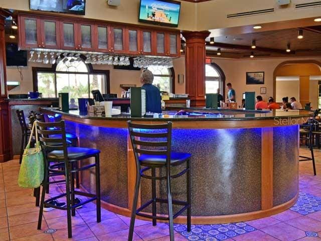 bar with decorative columns and light tile patterned flooring