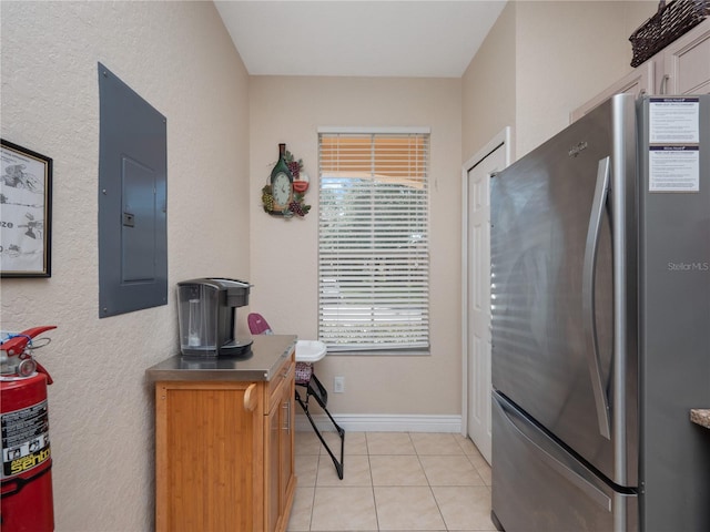 kitchen with light tile patterned floors, electric panel, and stainless steel refrigerator