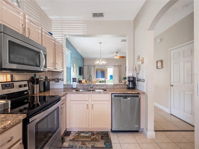 kitchen with light tile patterned flooring, sink, decorative light fixtures, appliances with stainless steel finishes, and backsplash