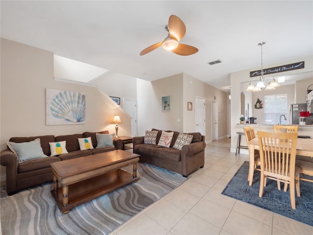 tiled living room featuring sink and ceiling fan with notable chandelier