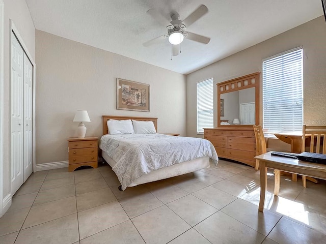 tiled bedroom with ceiling fan and a closet