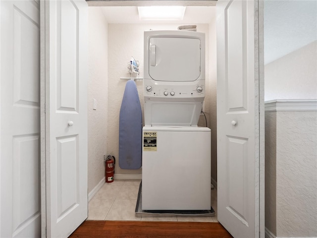 laundry area with stacked washer and clothes dryer and light tile patterned floors