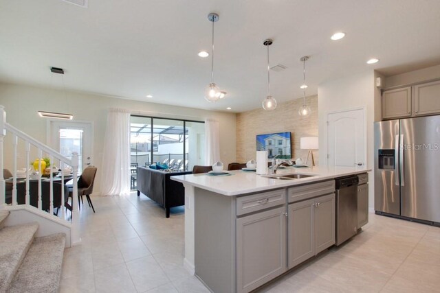 kitchen with gray cabinets, a kitchen island with sink, appliances with stainless steel finishes, and sink