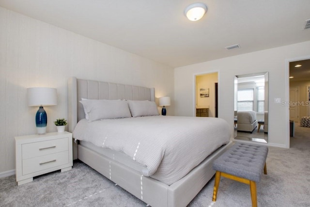 bedroom with ensuite bath and light colored carpet