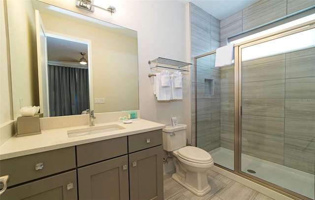 bathroom featuring vanity, ceiling fan, tile floors, toilet, and a shower with shower door