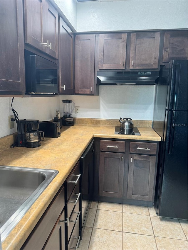 kitchen with dark brown cabinets, black appliances, light tile patterned floors, and sink