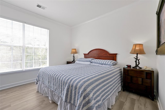 bedroom featuring light hardwood / wood-style flooring, crown molding, and multiple windows