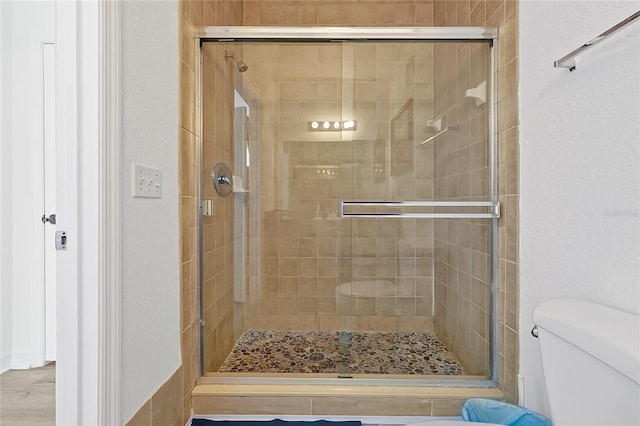 bathroom featuring toilet, hardwood / wood-style floors, and a shower with shower door