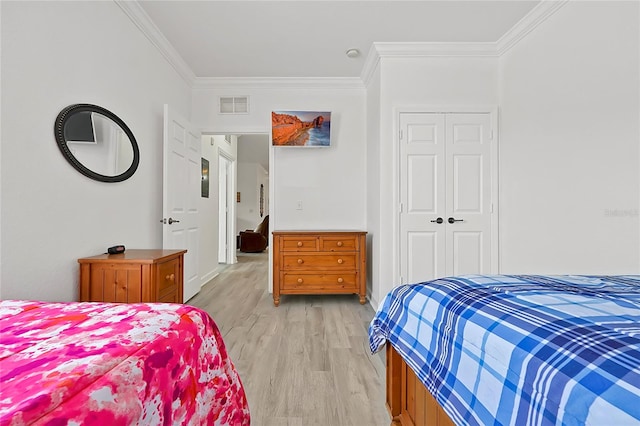 bedroom with light hardwood / wood-style floors, crown molding, and a closet