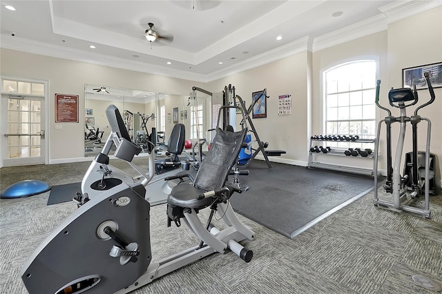 exercise room featuring carpet floors, crown molding, ceiling fan, and a tray ceiling