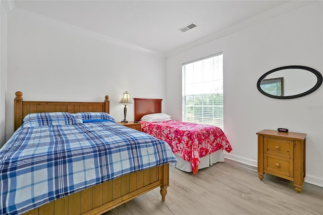 bedroom featuring light wood-type flooring and crown molding