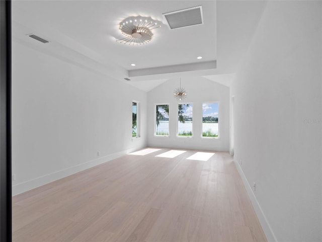 spare room with a chandelier, light hardwood / wood-style flooring, and lofted ceiling