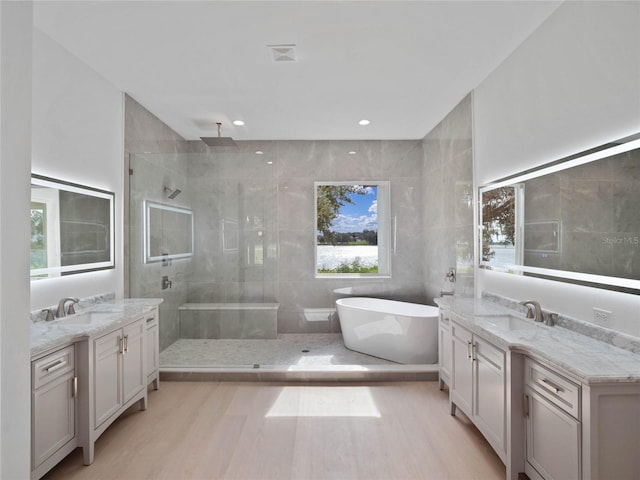 full bath with a tile shower, two vanities, and a sink