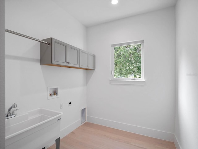 laundry room with baseboards, washer hookup, cabinet space, electric dryer hookup, and a sink