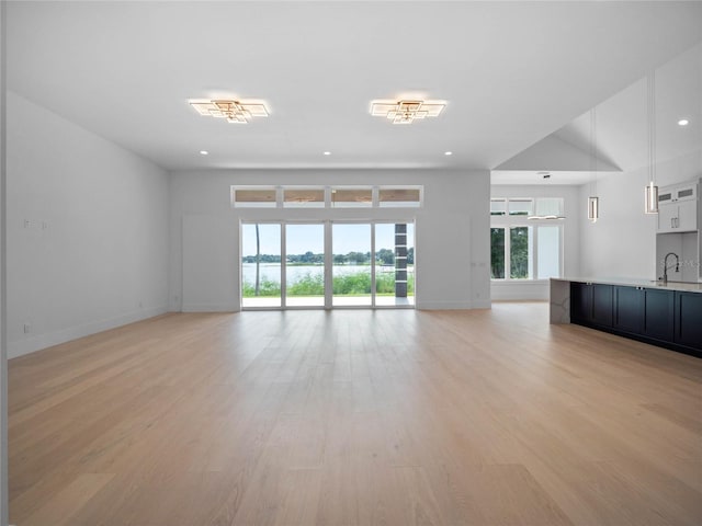 unfurnished living room featuring sink and light hardwood / wood-style floors