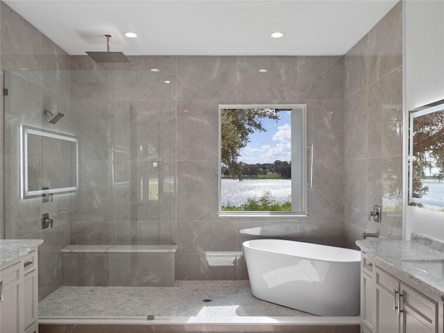 bathroom featuring a soaking tub, tile walls, vanity, and a walk in shower