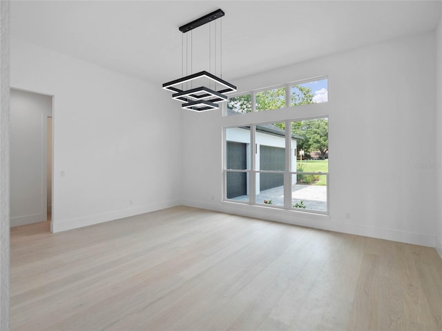 spare room with baseboards and light wood finished floors