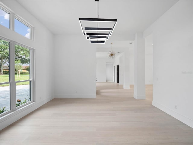 empty room with light hardwood / wood-style floors and a notable chandelier