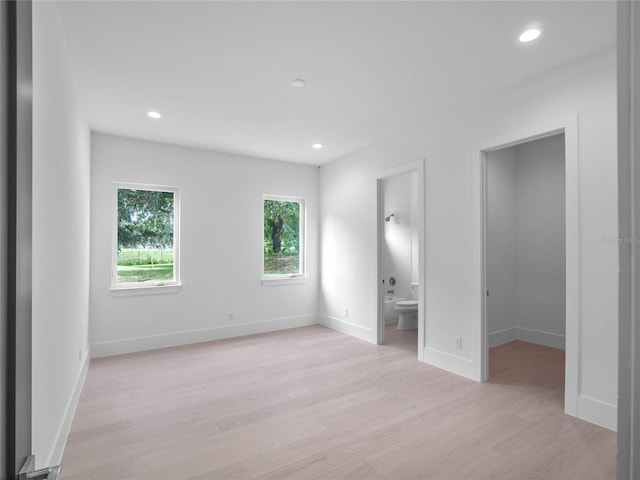 unfurnished bedroom with recessed lighting, baseboards, light wood-style floors, and a spacious closet