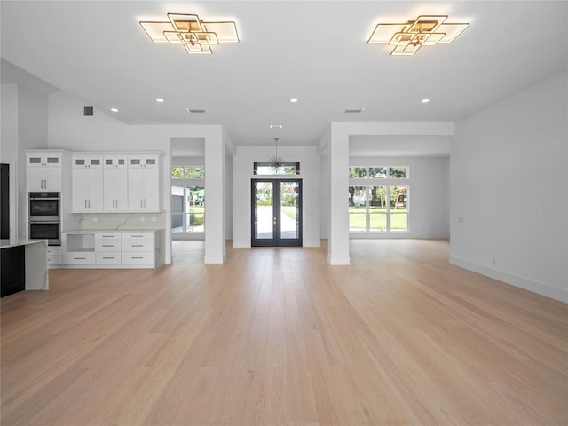 unfurnished living room with recessed lighting, french doors, and light wood-style flooring