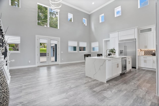 kitchen with light hardwood / wood-style flooring, tasteful backsplash, beverage cooler, and a healthy amount of sunlight