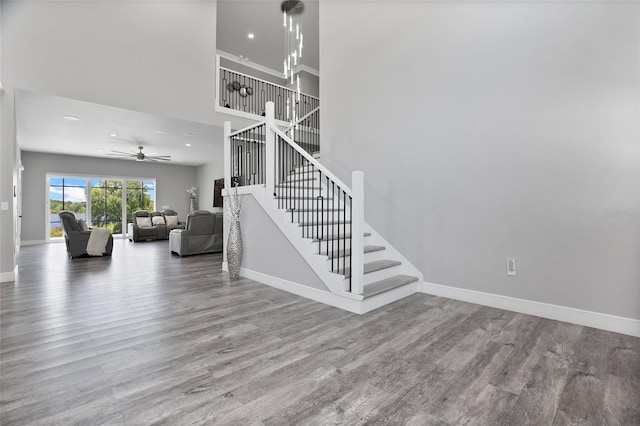 stairway featuring ceiling fan, hardwood / wood-style flooring, and a high ceiling