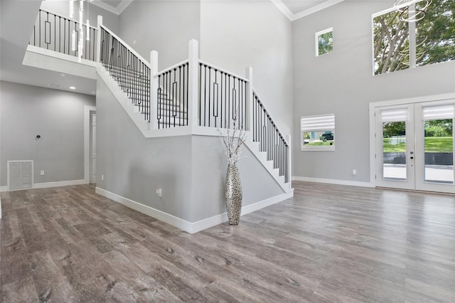 unfurnished living room featuring hardwood / wood-style floors, a towering ceiling, french doors, and a healthy amount of sunlight