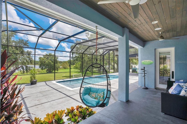 view of swimming pool with a patio area, glass enclosure, a yard, and ceiling fan