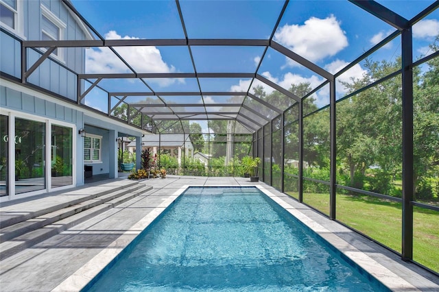 view of swimming pool with glass enclosure, a patio area, and a lawn