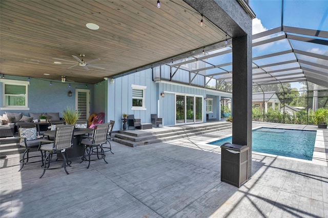 view of swimming pool featuring glass enclosure, ceiling fan, and a patio area