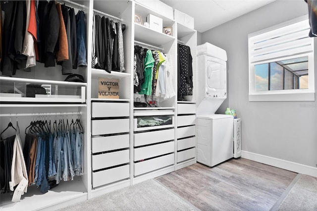 spacious closet featuring light hardwood / wood-style flooring and stacked washing maching and dryer