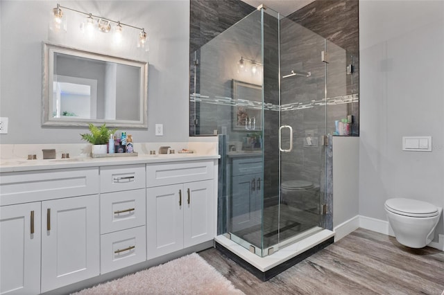 bathroom with double sink vanity, a shower with door, hardwood / wood-style flooring, and toilet