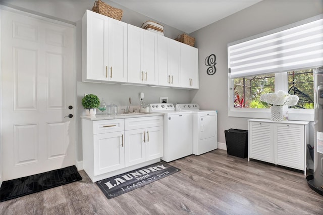 laundry room featuring separate washer and dryer, cabinets, sink, and light hardwood / wood-style floors