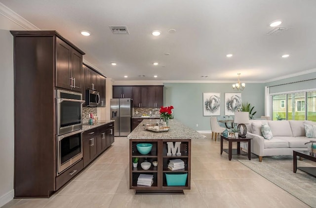 kitchen featuring appliances with stainless steel finishes, backsplash, hanging light fixtures, dark brown cabinetry, and a center island with sink