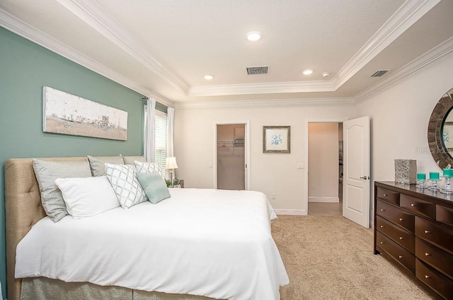 bedroom with light colored carpet, ornamental molding, a tray ceiling, and a spacious closet