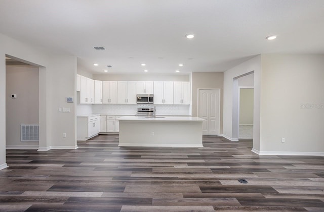 kitchen featuring dark wood-type flooring, sink, white cabinetry, tasteful backsplash, and a kitchen island with sink