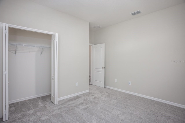 unfurnished bedroom with light carpet and a closet