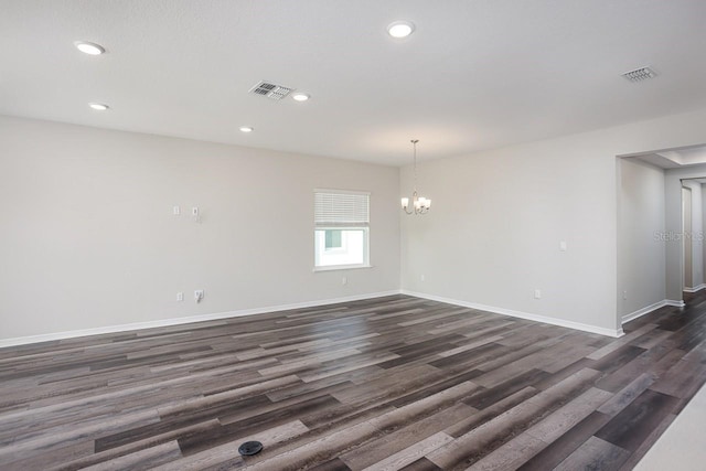 empty room featuring a notable chandelier and dark hardwood / wood-style flooring