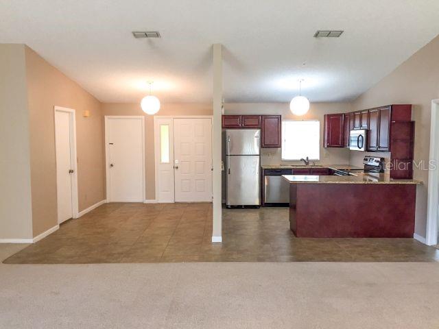 kitchen featuring carpet floors, pendant lighting, appliances with stainless steel finishes, and sink