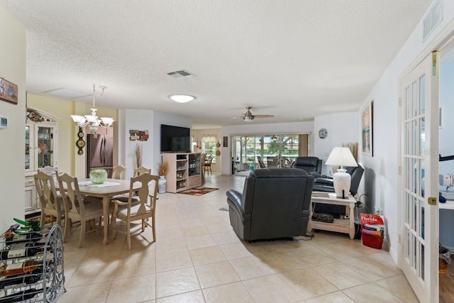 living room featuring light tile floors, a textured ceiling, and ceiling fan with notable chandelier