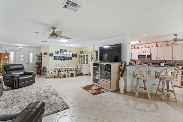 tiled living room with a textured ceiling and ceiling fan