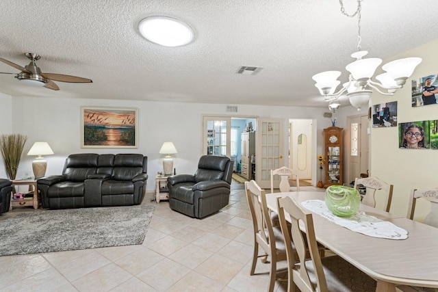 tiled dining area with a textured ceiling, french doors, and ceiling fan with notable chandelier