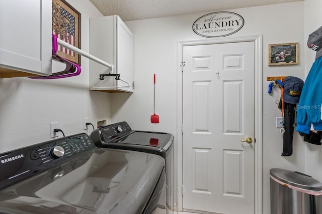 laundry room featuring washing machine and clothes dryer, washer hookup, cabinets, and a textured ceiling