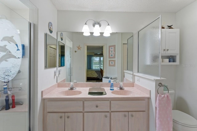 bathroom with toilet, large vanity, double sink, and a textured ceiling