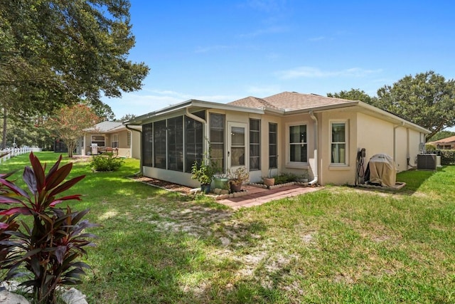 back of property featuring a lawn, a sunroom, and central air condition unit