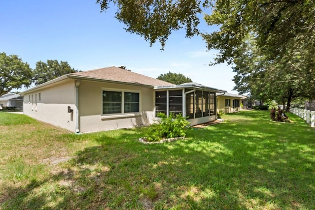 back of property featuring a lawn and a sunroom