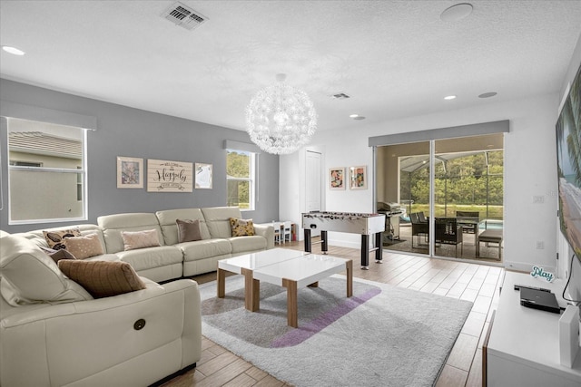 living room featuring a chandelier, light hardwood / wood-style floors, and a textured ceiling