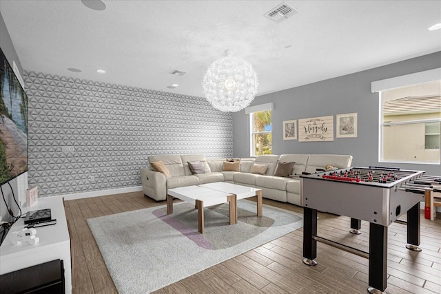 recreation room with a chandelier, hardwood / wood-style floors, and a textured ceiling