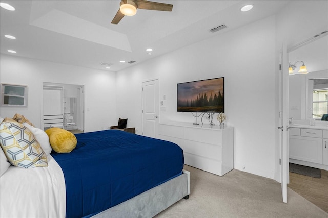 carpeted bedroom with ceiling fan, a tray ceiling, and connected bathroom