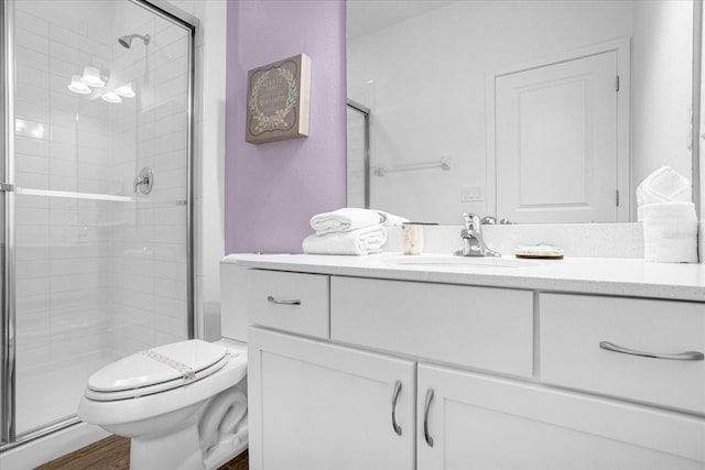 bathroom with wood-type flooring, toilet, a shower with shower door, and vanity